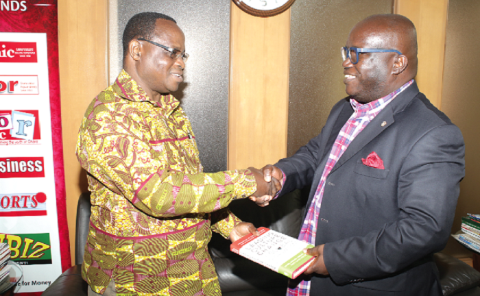 Mr Kenneth Ashigbey (right), Managing Director of the Graphic Communications Group Limited, presents a book to Mr Felix Abayateye, the outgoing  Editor of the Graphic Sports.